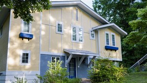 A two-story house with a blue door and windows, number 365, surrounded by greenery and a stone wall. - Spacious 6-bedroom house with WiFi & AC in charming Jamestown lake ramp access (Jamestown)