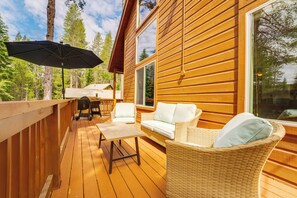 A wooden deck with outdoor furniture, including a table and chairs, and a wicker chair with cushions.