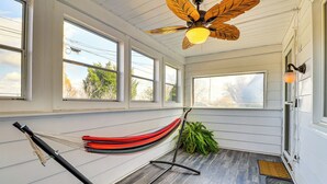 A room with large windows, a hammock, and a ceiling fan. - Game Room & Fire Pit: West Mifflin Home! (West Mifflin)