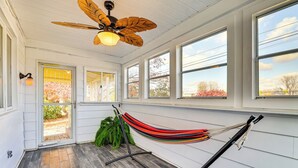 A room with a hammock, large windows, and a ceiling fan. - Game Room & Fire Pit: West Mifflin Home! (West Mifflin)