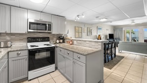 A modern kitchen with stainless steel appliances, grey cabinetry, and a central island. - Enjoy a spacious, low-rise Sugar Beach condo with a private beach entrance, pool, sunset views, and glimpses of the Gulf. The condo sleeps up to 10 and is close to dining and local attractions in Panama City Beach. (Panama City Beach)