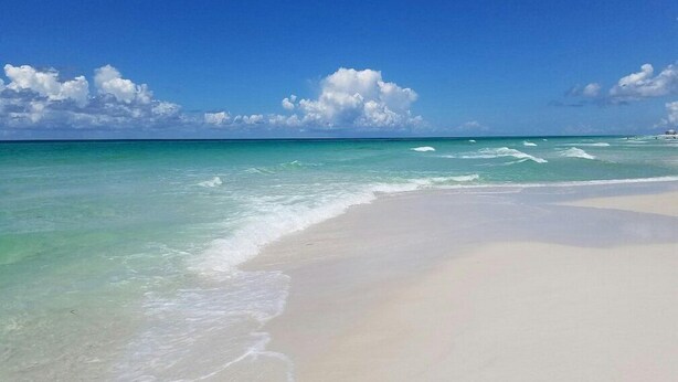 A beach with clear turquoise water and white sand. - Enjoy a spacious, low-rise Sugar Beach condo with a private beach entrance, pool, sunset views, and glimpses of the Gulf. The condo sleeps up to 10 and is close to dining and local attractions in Panama City Beach. (Panama City Beach)