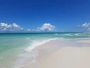 Een strand met helder turquoise water en wit zand.