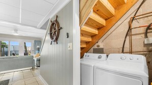 A laundry area with a washing machine and a wooden ceiling. - Enjoy a spacious, low-rise Sugar Beach condo with a private beach entrance, pool, sunset views, and glimpses of the Gulf. The condo sleeps up to 10 and is close to dining and local attractions in Panama City Beach. (Panama City Beach)