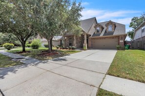 A residential house with a garage, a driveway, and a well-maintained lawn. - Pool Volleyball Oasis |Sleeps 18 (Houston)