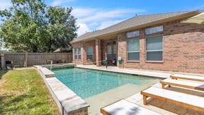 A backyard with a swimming pool, a brick house, and outdoor seating. - Pool Volleyball Oasis |Sleeps 18 (Houston)
