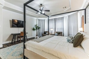 A modern bedroom with a large bed, a desk, a chair, a TV, and a ceiling fan. - Pool Volleyball Oasis |Sleeps 18 (Houston)