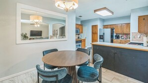Une cuisine moderne avec un coin repas, comprenant un îlot central, des meubles de cuisine en bois et un lustre.