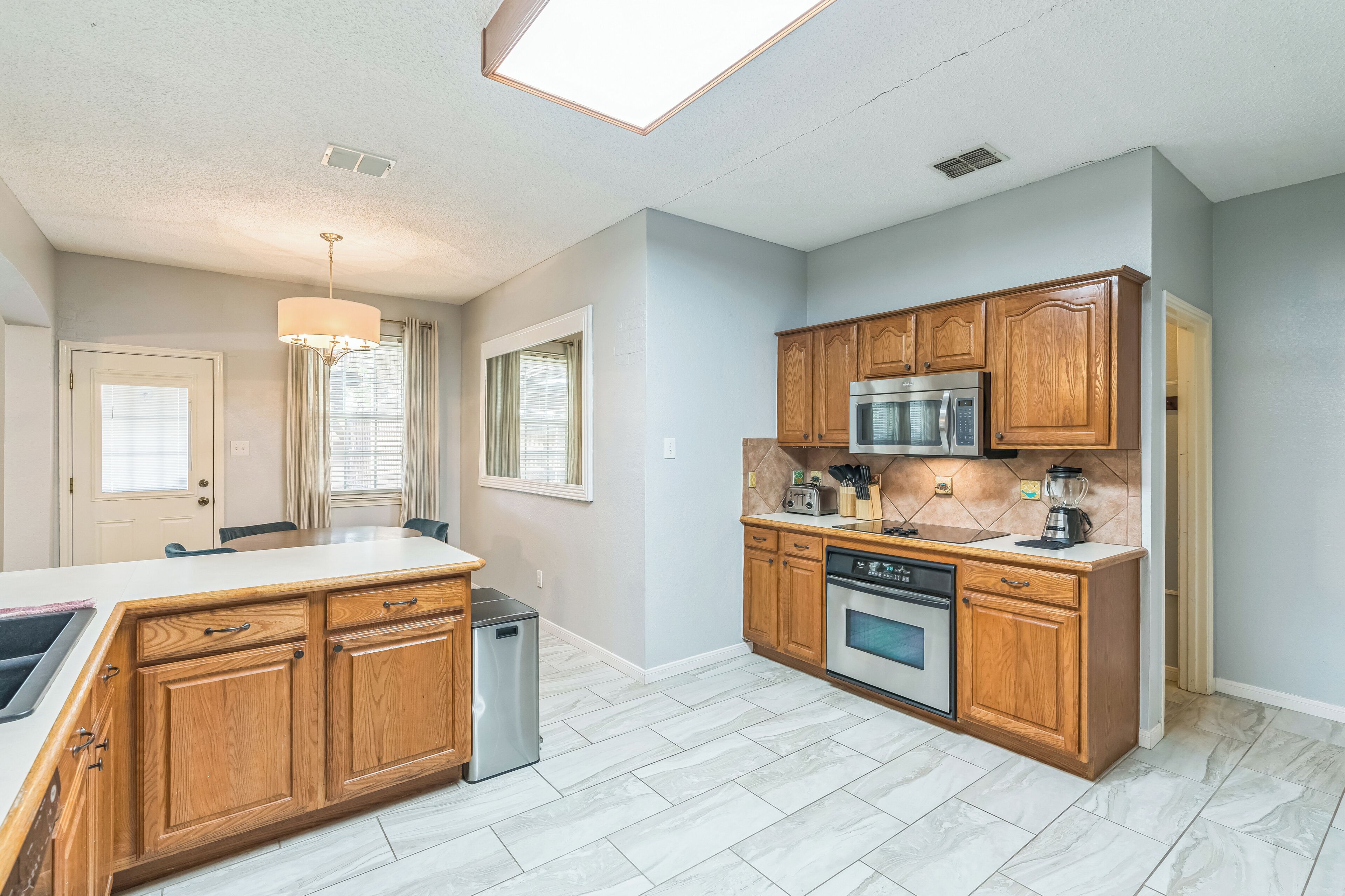 A modern kitchen with wooden cabinets, stainless steel appliances, and a large island with a sink.