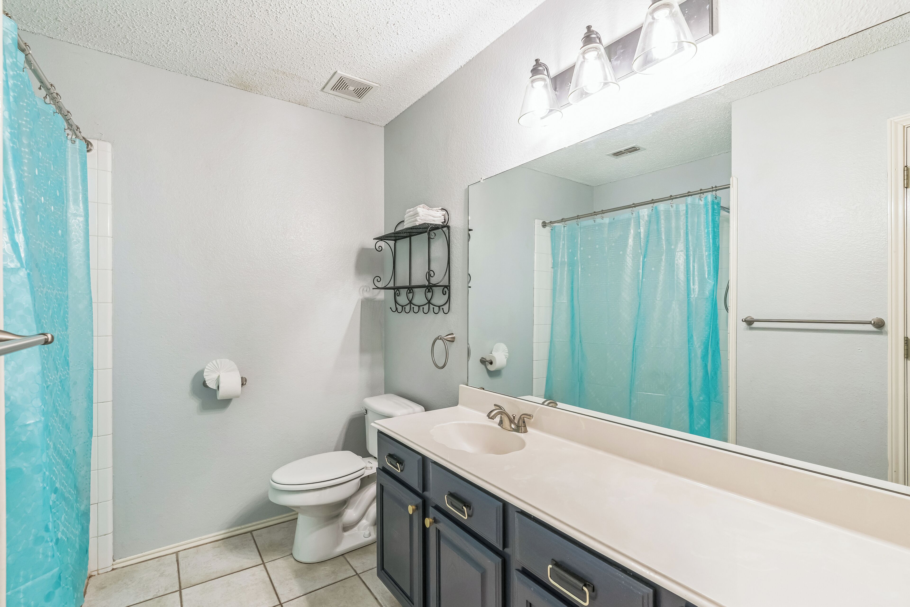 A bathroom with a white toilet, a sink with a mirror, and a shower curtain.