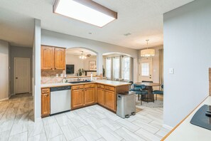 A modern kitchen with wooden cabinets, a dishwasher, and a stainless steel refrigerator. - Rockwall Retreat | Pool, Games & King Beds (Rockwall)