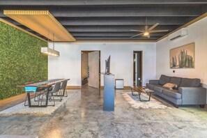 A modern living space with a dining area, a sofa, and a ceiling fan.