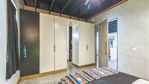 Een slaapkamer met een bed, een kledingkast en een deur naar een andere kamer.
