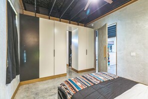 A bedroom with a bed, a wardrobe, and a door leading to another room.