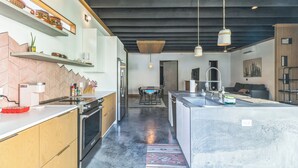 Een moderne keuken met een centraal eiland, inbouwapparatuur en hangende lampen.