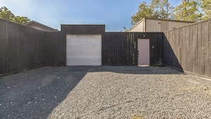 Een omheinde achtertuin met een grindpad en een gesloten garage.
