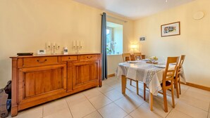 Uma área de refeições com um armário de madeira, uma mesa posta para quatro pessoas e um candelabro.