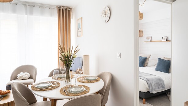 Ein Essbereich mit einem runden Tisch, gedeckt für vier Personen, einer Blumenvase und einer Uhr an der Wand.