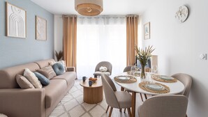 Ein modernes Wohnzimmer mit Sofa, Couchtisch und Esstisch für zwei Personen.