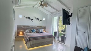 A bedroom with a bed, a ceiling fan, a mounted TV, and a view of the outdoors. - COCO SAI, where you will see the majesty of the sea and the sky as one.  (San Andrés)