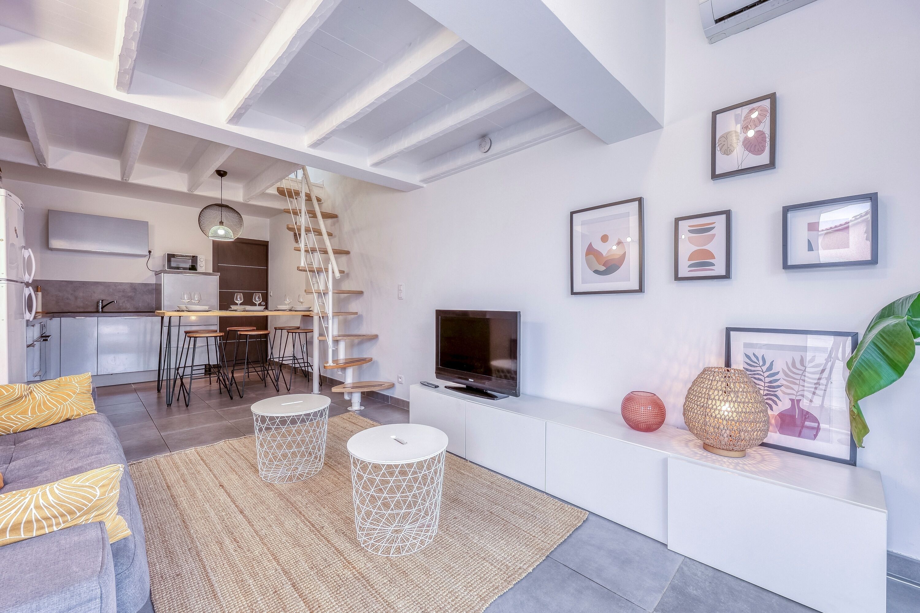 Una sala de estar moderna con sofá, mesa de centro, televisión y obras de arte en la pared.