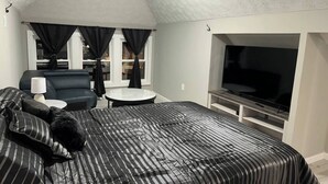 Una habitación pequeña con cama, sofá, una mesita y televisión.