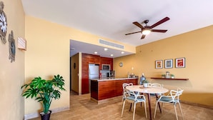 A modern kitchen with a central island, a dining area with a round table and chairs, a ceiling fan, and a potted plant. - 1BR Oceanview Condo w/pool (Isla Mujeres)