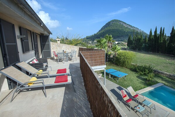 Una terraza en la azotea con sillones, una piscina y vistas a la montaña.