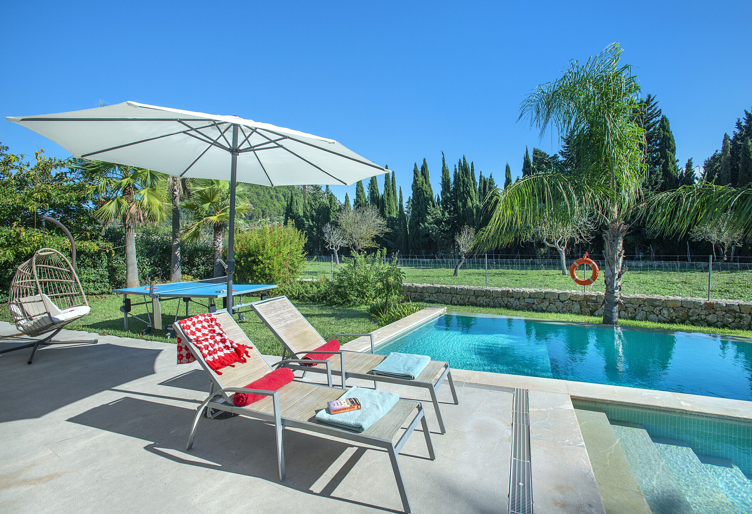Un espace aménagé au bord de la piscine, avec des chaises longues, une table et un parasol.