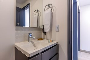 Bathroom features a vanity with a large mirror, towel racks, and a single faucet.
