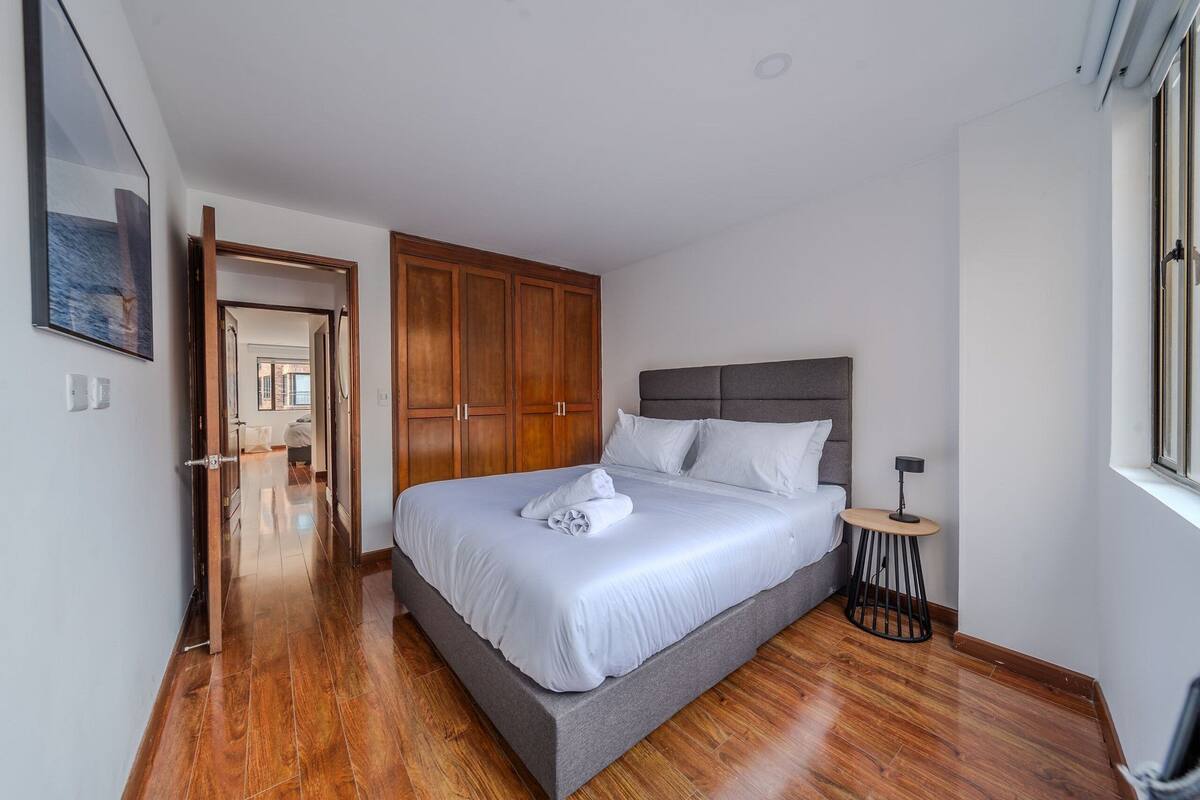 Une chambre moderne avec un grand lit, une armoire en bois et une petite table ronde.