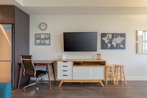 A modern office space with a desk, chair, and a large flat-screen TV.