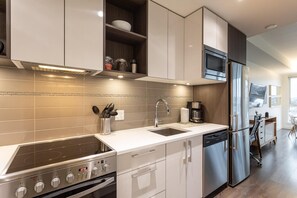 A modern kitchen with a built-in oven, a stainless steel refrigerator, and a coffee maker. - Bright and Trendy Heritage Suite in Old Town (Victoria Central British Columbia Provincial Government)
