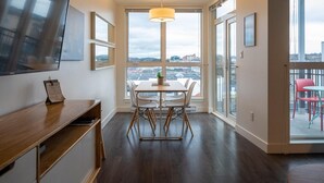 Ein moderner Essbereich mit Tisch und Stühlen, einer Pendelleuchte und Blick auf die Stadt durch große Fenster.