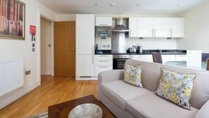 Ein modernes Wohnzimmer mit Sofa, Couchtisch und einer Küche im Hintergrund.