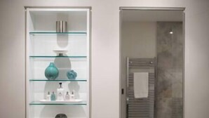 A bathroom with a glass display cabinet containing toiletries and a towel rack with a towel.