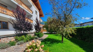 A multi-story building with a stone pathway leading to a well-maintained garden. - Panorama App 1B Zell am See (Zell am See)