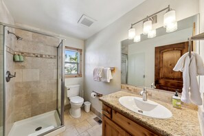 A modern bathroom with a glass-enclosed shower, a white sink, and a large mirror.