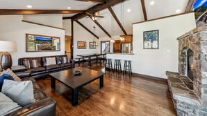 A spacious living area with a dark wooden floor, leather sofa, and a stone fireplace. - Top of Kingsbury View Home 7BR,4BA,Spa, 5 To Ski (Stateline)