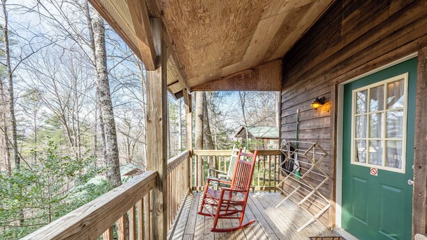 A wooden deck with a rocking chair and a green door.