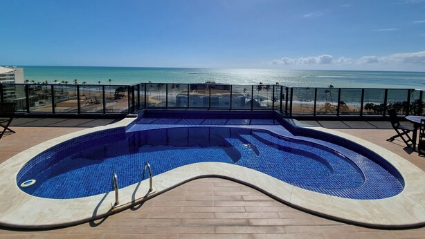 Ein Schwimmbad mit Blick auf den Ozean und den Strand.