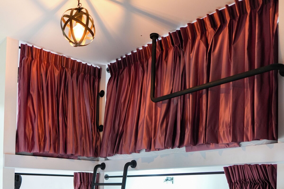 A bunk bed room with two beds, a ladder, and a hanging light fixture.