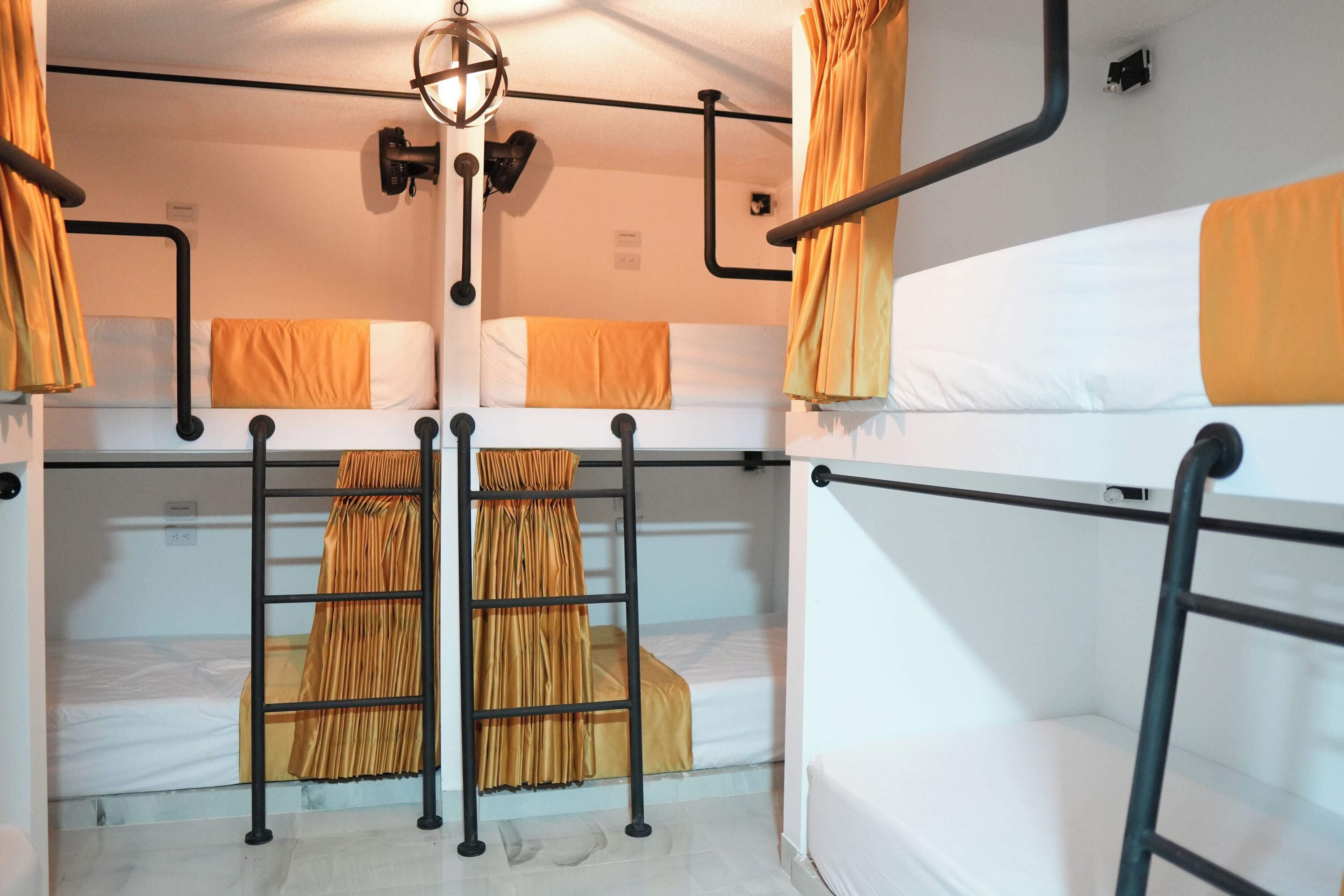 Ein Schlafsaalzimmer mit Etagenbetten, einer Stehleiter und einer Pendelleuchte.