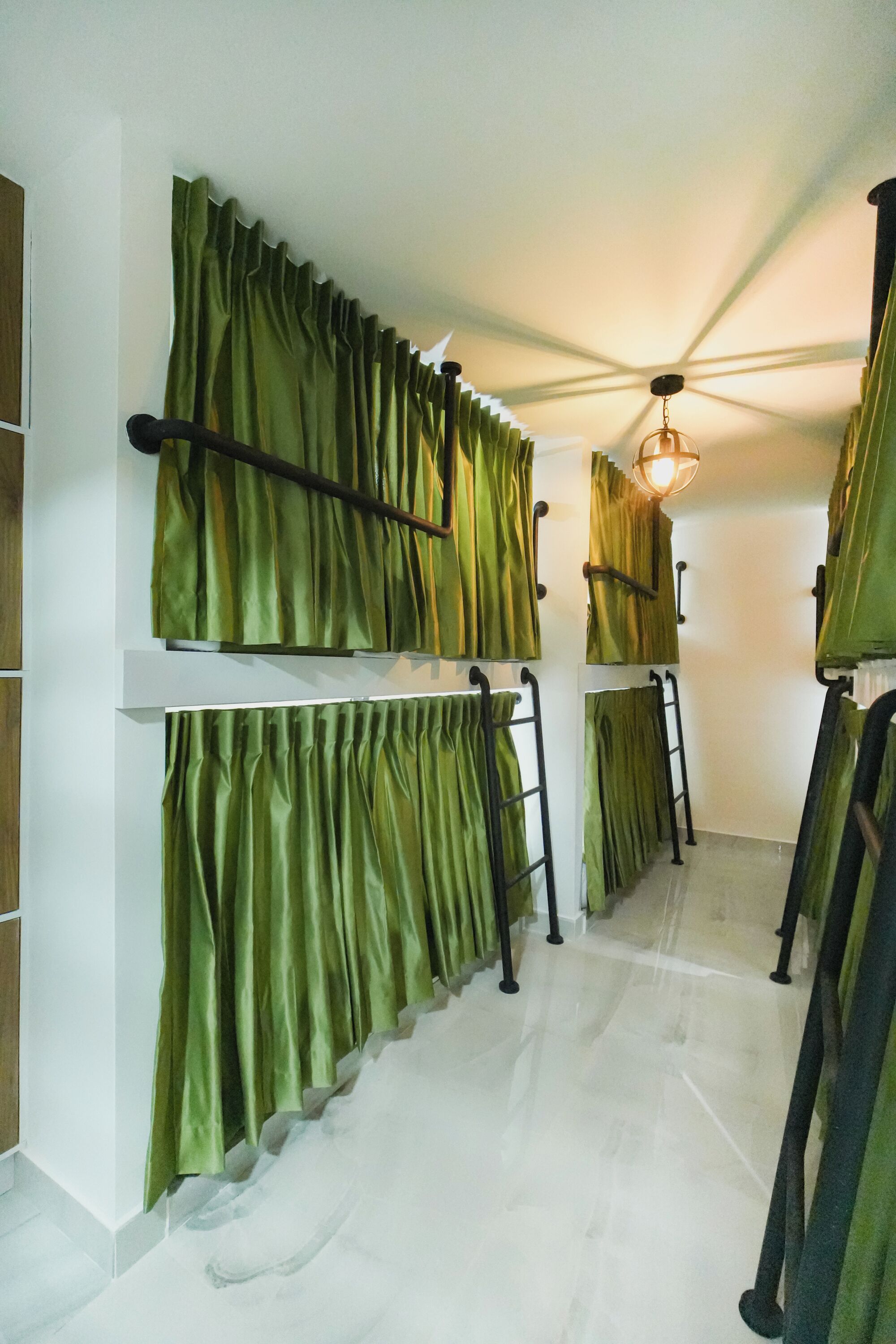 A room with bunk beds, green curtains, a ceiling fan, and a light fixture.