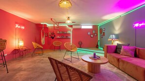 A modern living room with a red and pink color scheme, featuring wicker chairs, a round coffee table, and a sofa. - Casa Zafiro B&B (San Pedro)