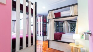 A bunk bed room with a wooden floor, a bedside table with a lamp, and a window with curtains. - Casa Zafiro B&B (San Pedro)