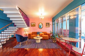 Uma sala de estar moderna com escadas, um sofá, uma mesa de centro e uma área de jantar com cadeiras.