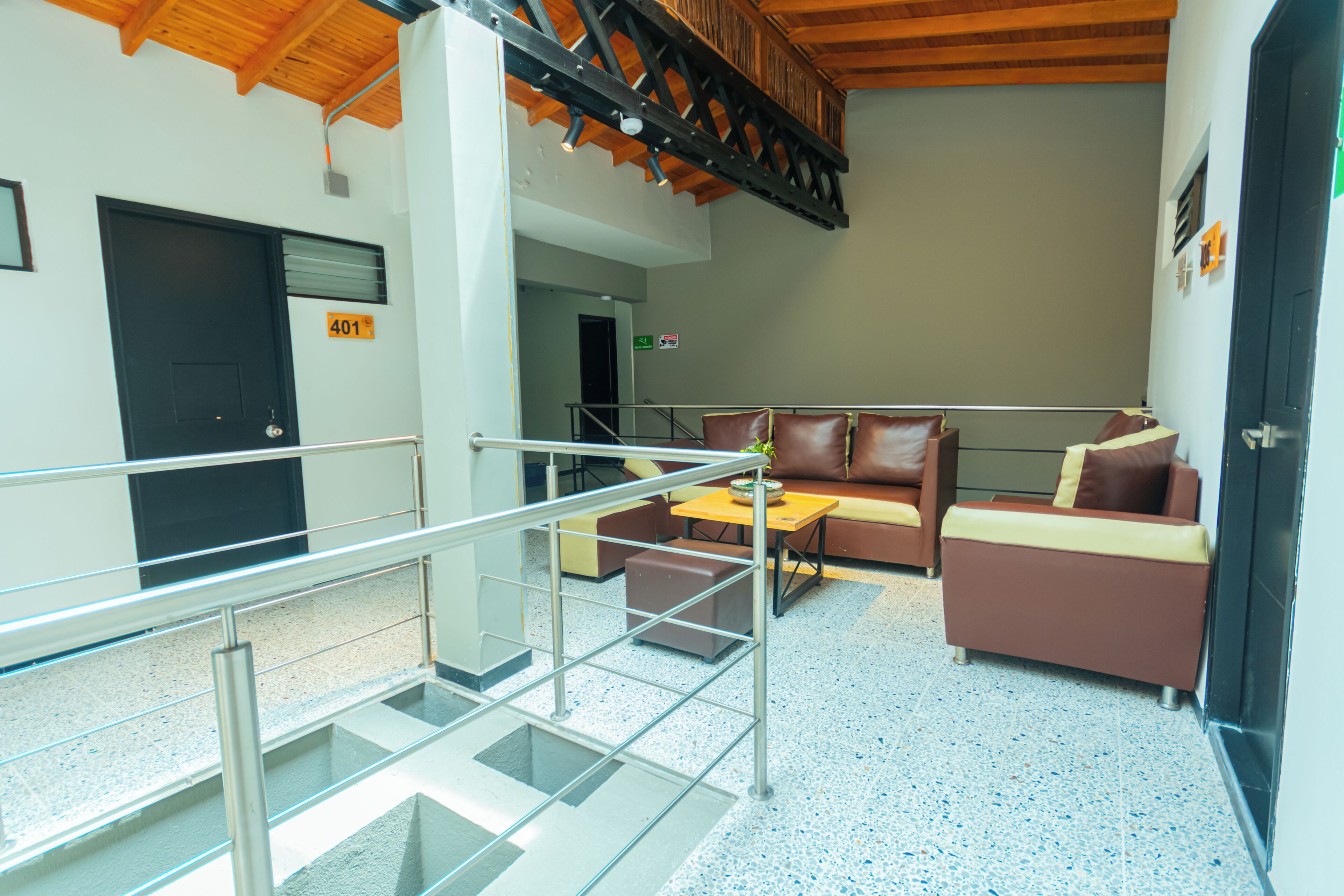 A hotel lobby with a staircase, a sofa, a coffee table, and a door marked '401'.