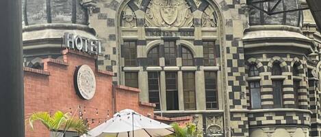 Un hotel con una fachada distintiva a cuadros, un reloj prominente y un paraguas grande en primer plano.