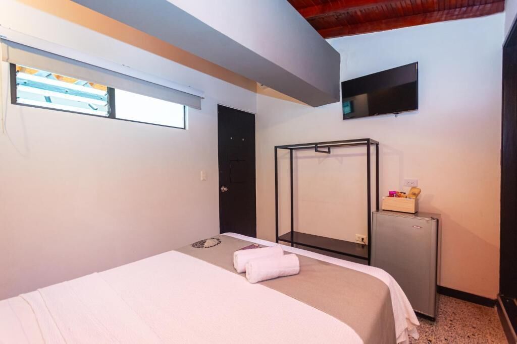 Ein Hotelzimmer mit Bett, Schreibtisch, Fernseher und Fenster.